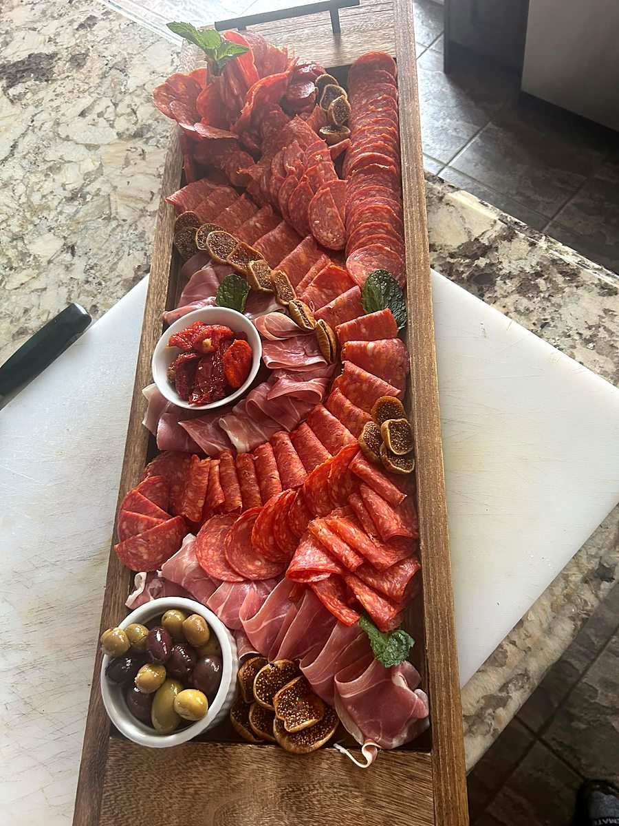 Long charcuterie board with cured meats, cheeses and preserves for an event