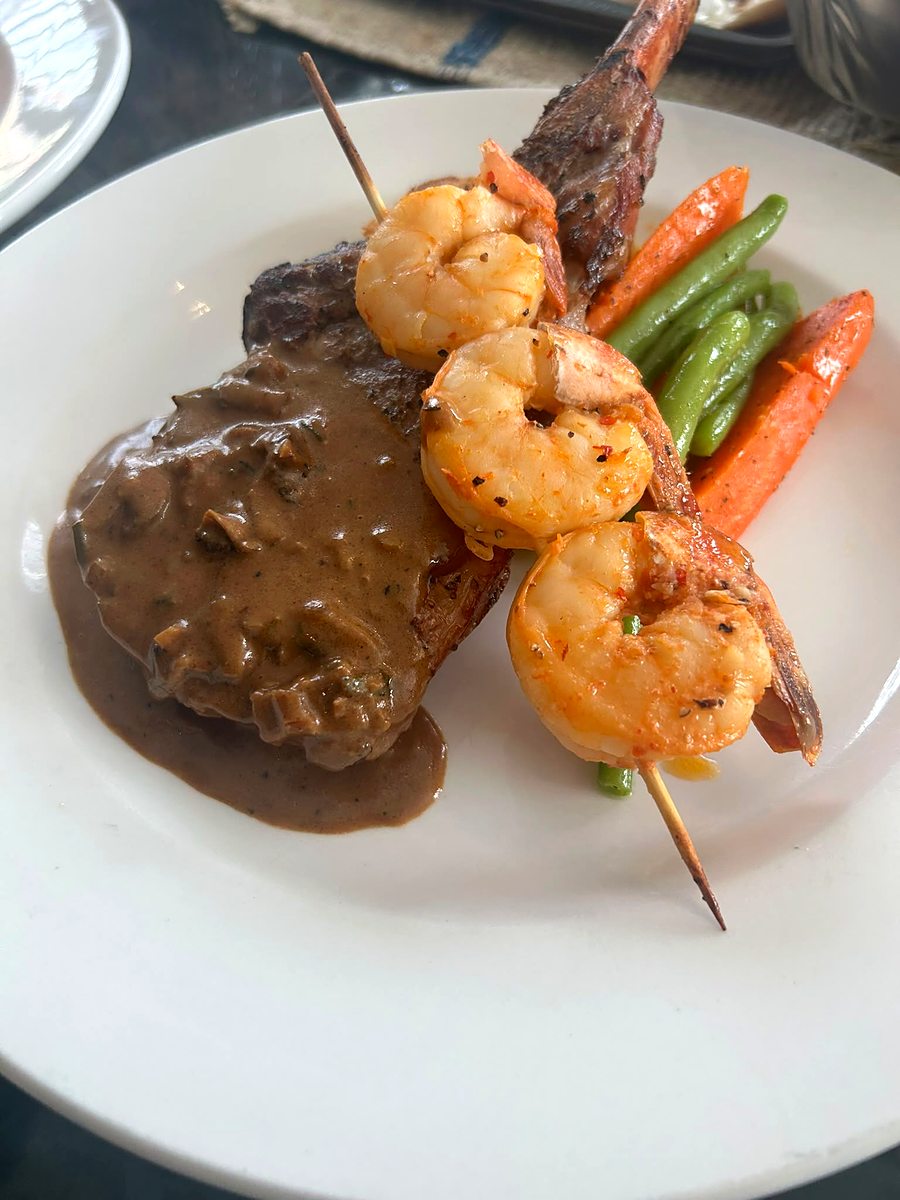 Plated duo main of steak and shrimp skewer with seasonal vegetables