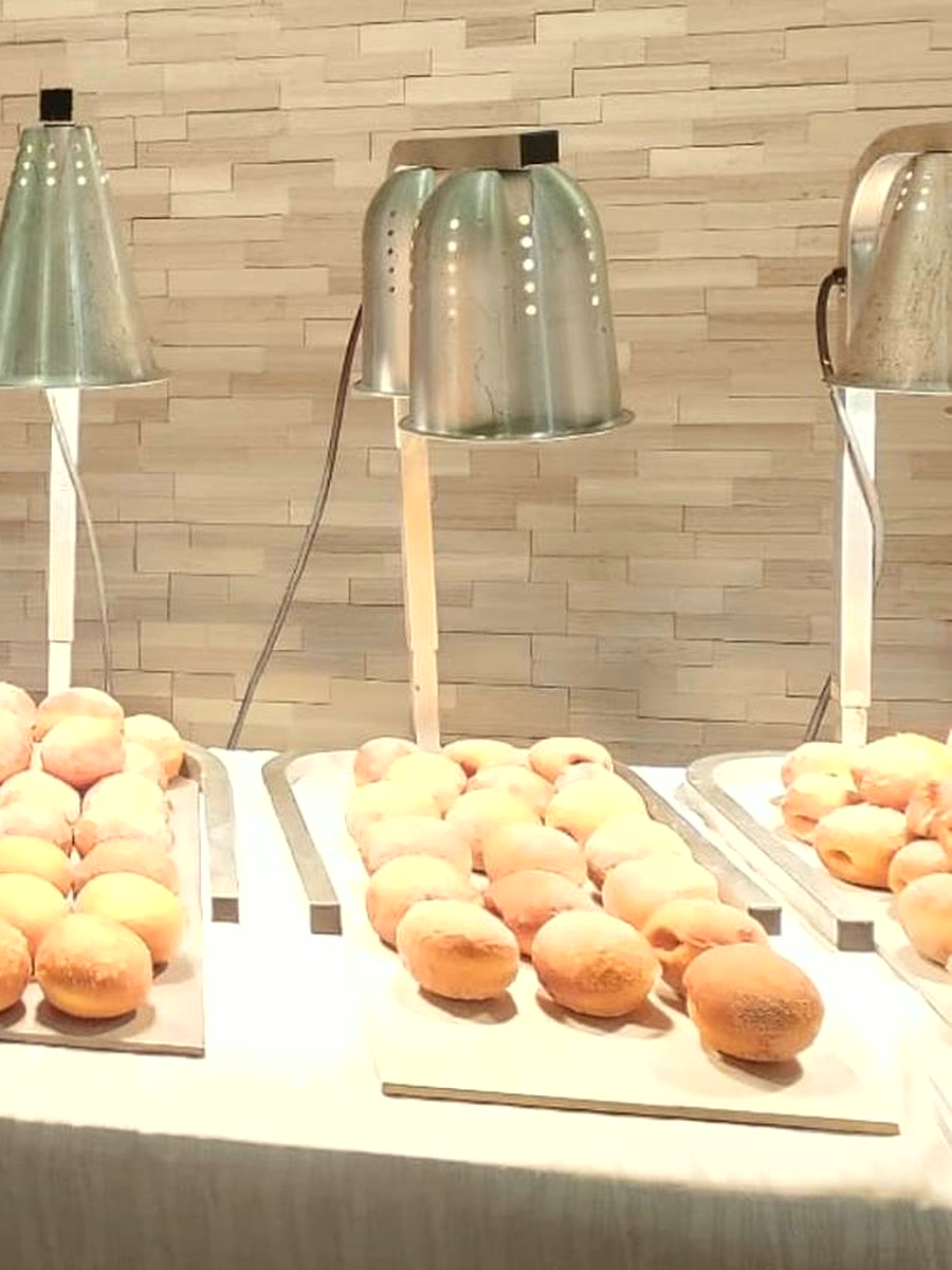 Live malasada station — trays of fresh Portuguese donuts under heat lamps