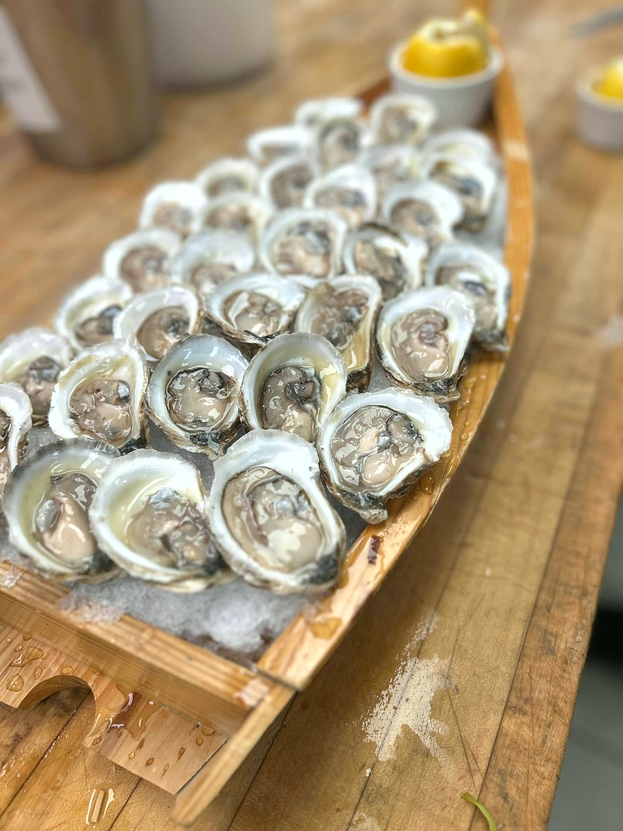 Fresh-shucked oysters on ice in a wooden serving boat
