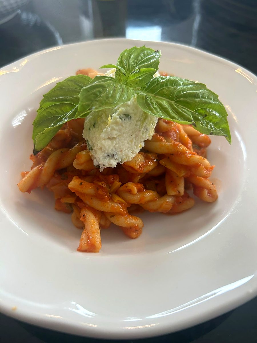 Pasta course topped with creamy burrata, plated close-up