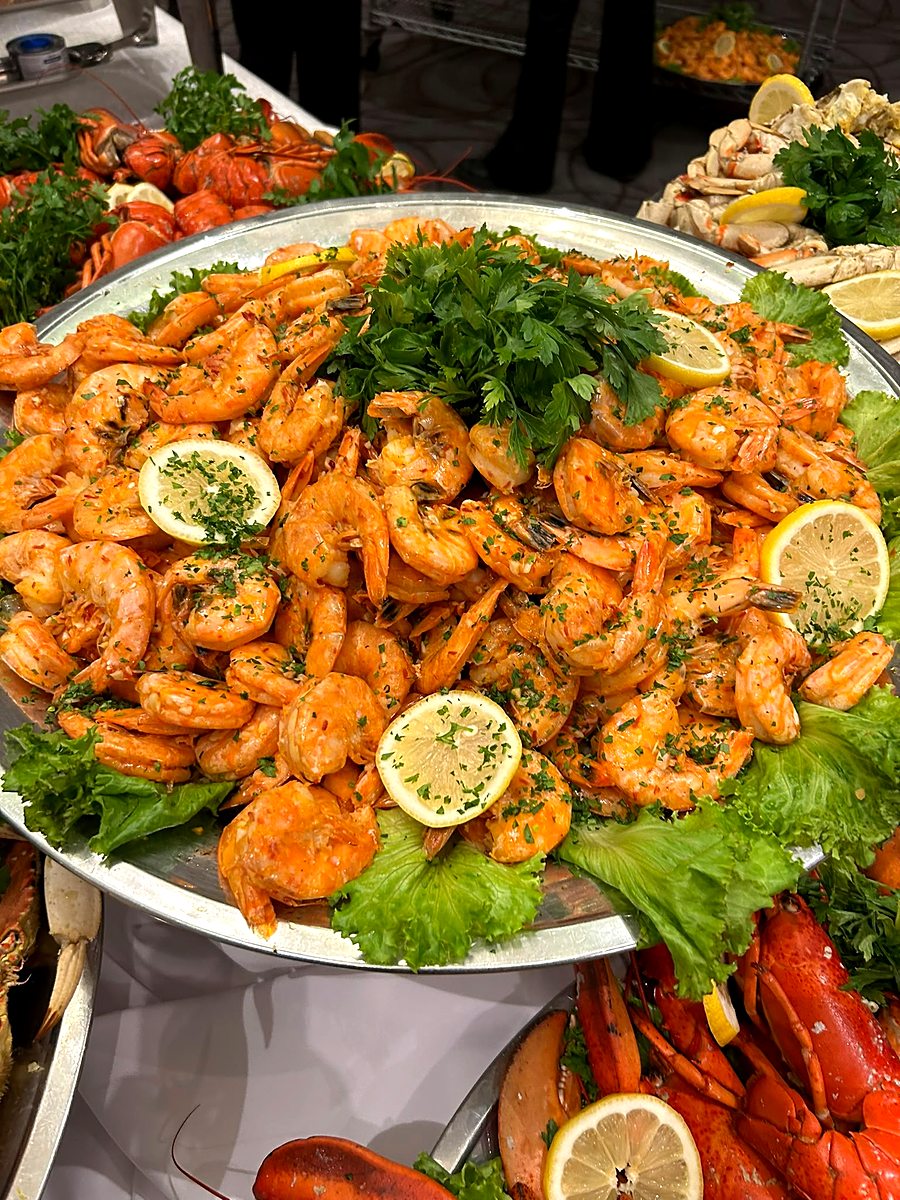 Large platter of seasoned tiger shrimp with lemon and fresh herbs