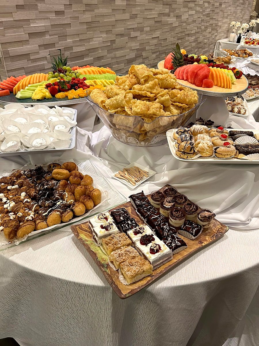 Late-night sweet table with sliced fruit, pastries and croquettes