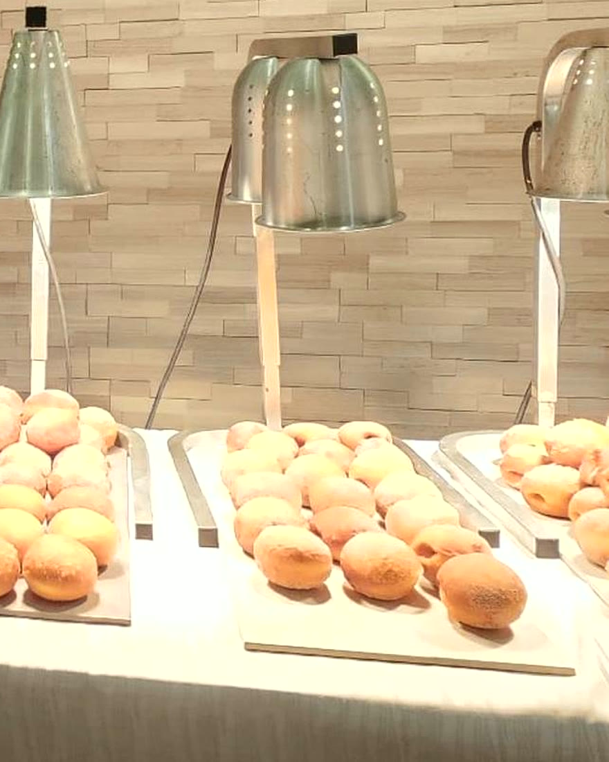 Trays of fresh malasadas under heat lamps at a CF Culinary Events live station