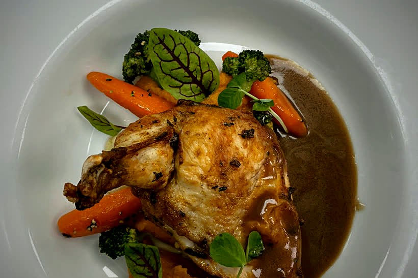 A plated roast chicken supreme with glazed carrots, broccoli and pan jus, ready to travel
