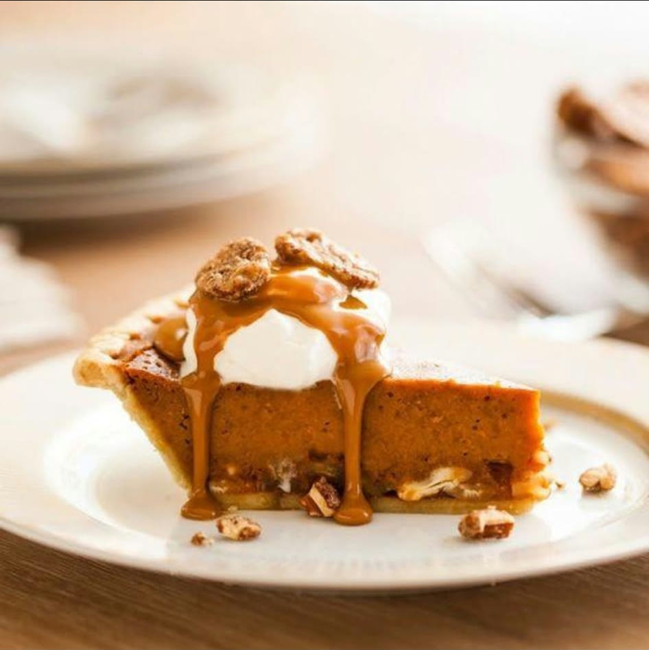 A slice of pumpkin pie with Chantilly cream and candied pecans