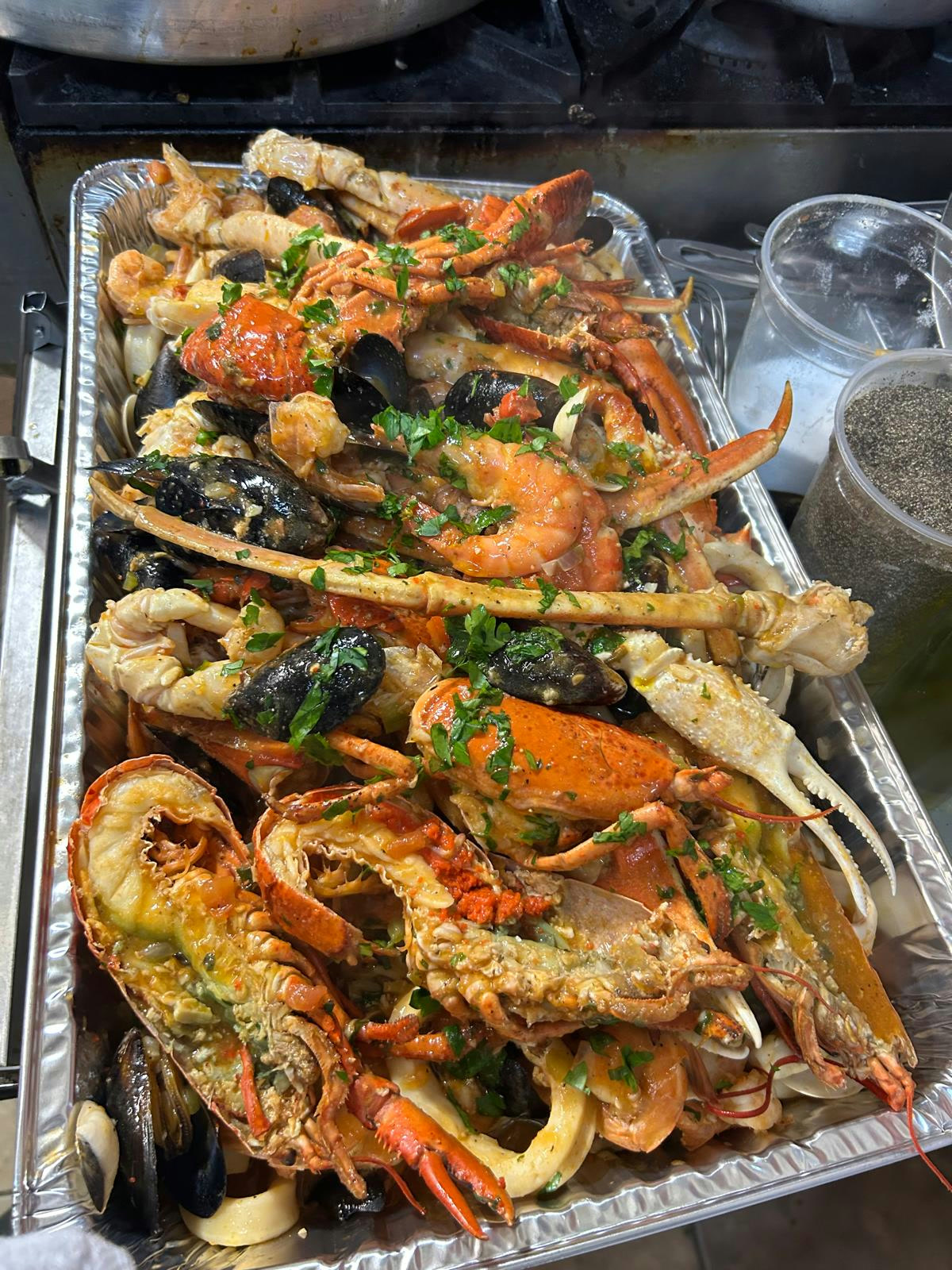 A CF Culinary Events seafood tray — lobster, crab legs, shrimp and mussels with garlic, herbs and white wine